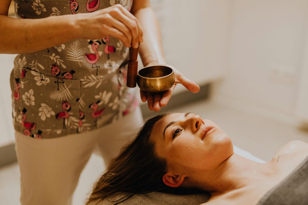 Young woman experiencing relaxation therapy with a singing bowl indoors.
